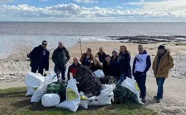 People standing on beach with rubbish bags they've collected