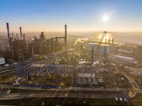 le soleil se lève derrière la raffinerie et l'unité HDT VGO en construction