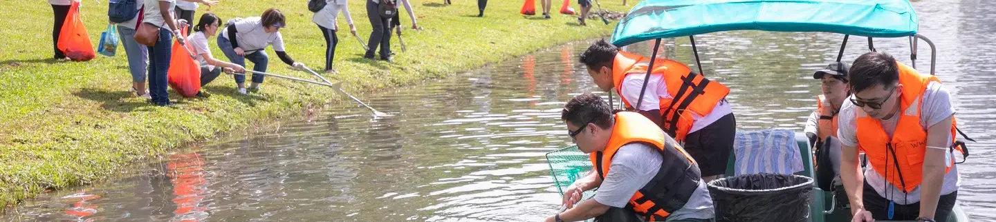 employee volunteers picking up litter along Marina Reservoir