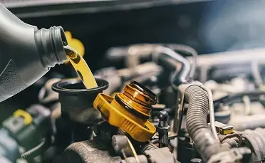 Bottle of engine oil being poured into a car engine