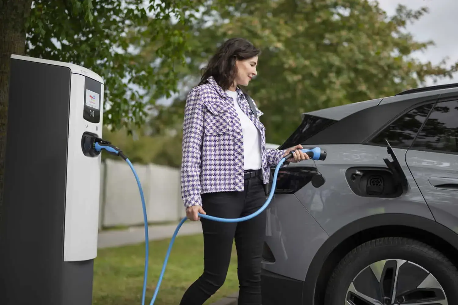 Frau beim elektrischen laden an Ladesäule von TotalEnergies 