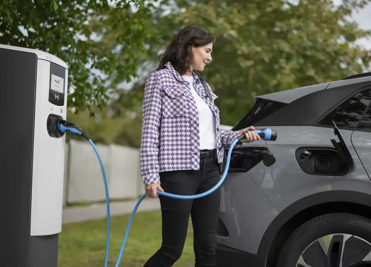 Frau beim elektrischen laden an Ladesäule von TotalEnergies