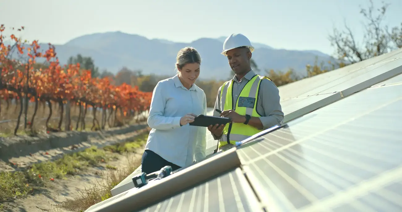 Two people talking next to solar panels