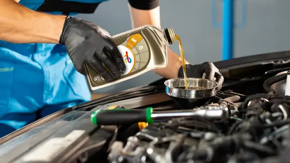 Mecánico en taller automotriz trabajando en el motor de un automóvil.