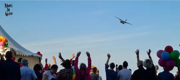 Plan in the sky and people with hands up in the air