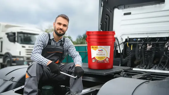 Mecánico usando aceite Rubia de TotalEnergies en motor de camión.