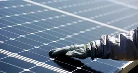 A gloved hand on a solar panel of the photovoltaic power plant started up by ISE, TotalEnergies​ and SunPower in Nanao, Japan.
