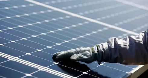A gloved hand on a solar panel of the photovoltaic power plant started up by ISE, TotalEnergies​ and SunPower in Nanao, Japan.