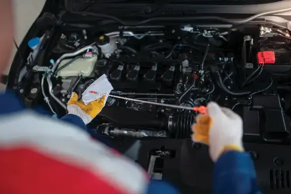 mechanic using a dip stick to check engine oil