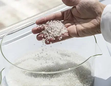 A hand holds polymers pellets