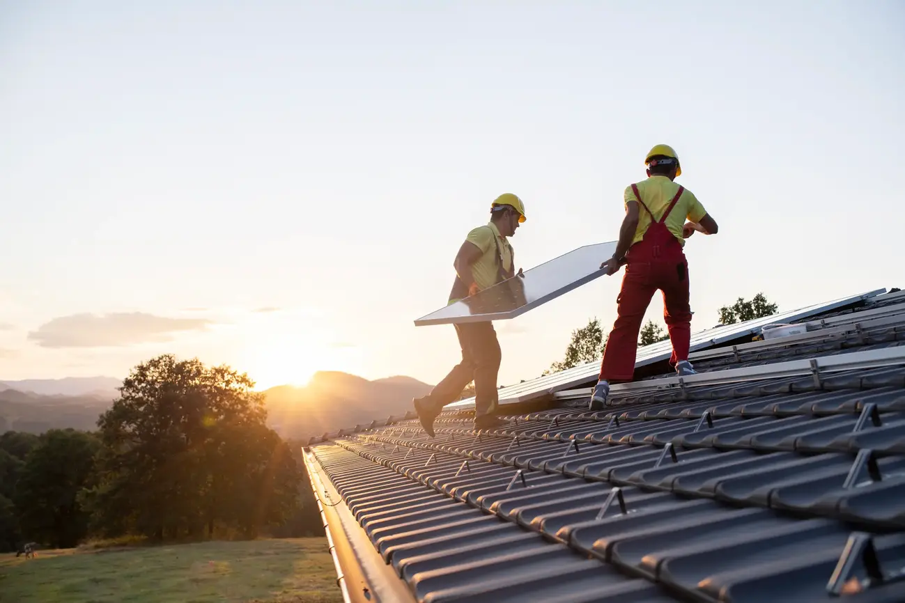 An image of two individuals carrying a solar panel.