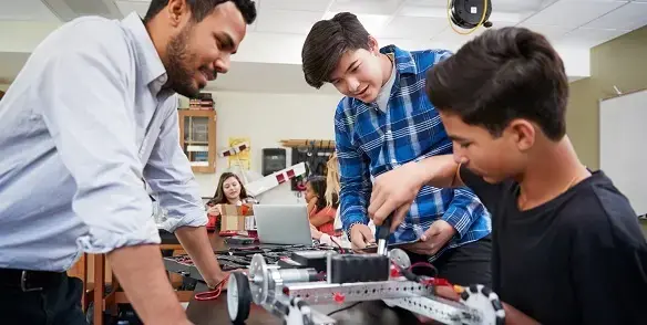 Teacher and school children talking whilst they build an object