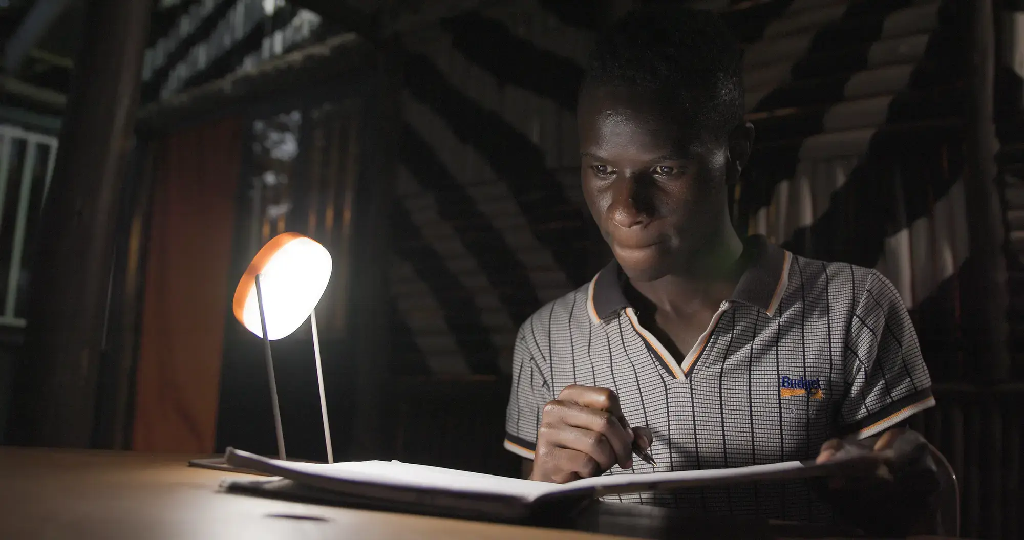 man working in a dark room using One Sunshine solar lamp