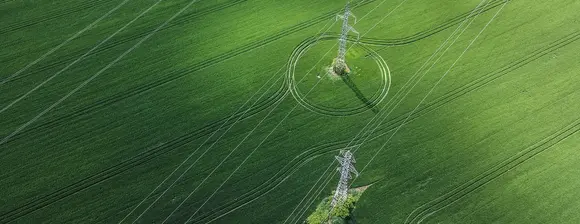 Big green grass field with two electricity plylons standing in it