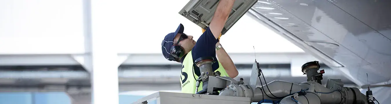 Flugzeugtechniker öffnet eine Klappe am Flugzeug