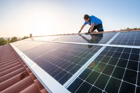 Person auf Dach mit Solarpanel und Sonne