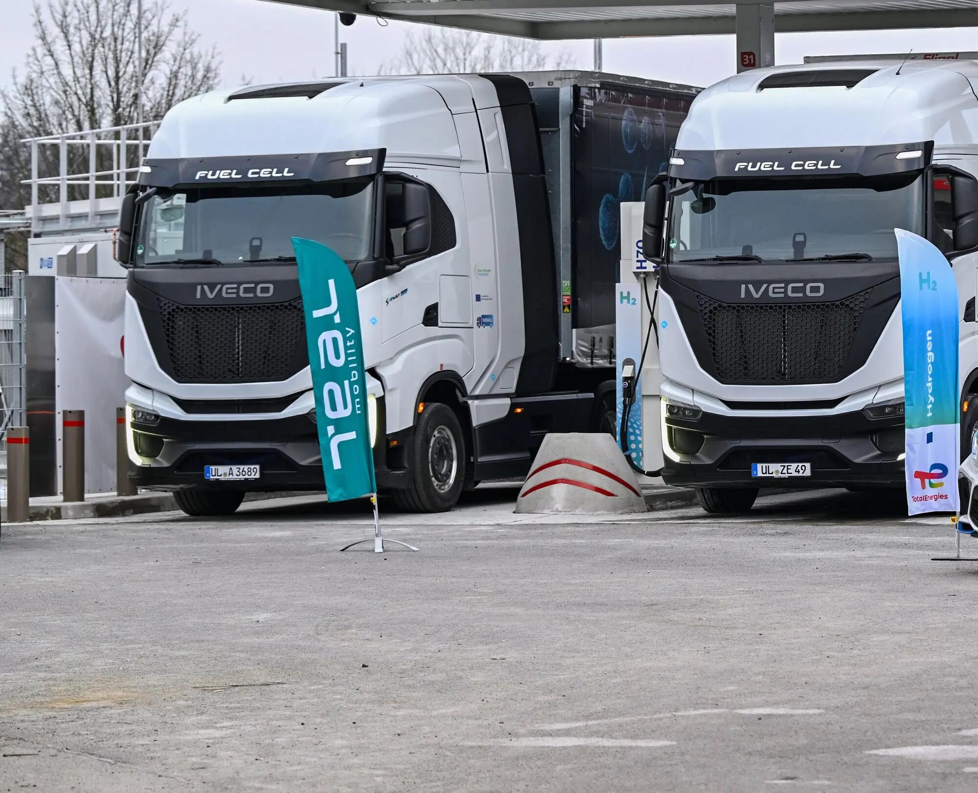 2 LKW mit TEAL und TotalEnergies Banner im Vordergrund 