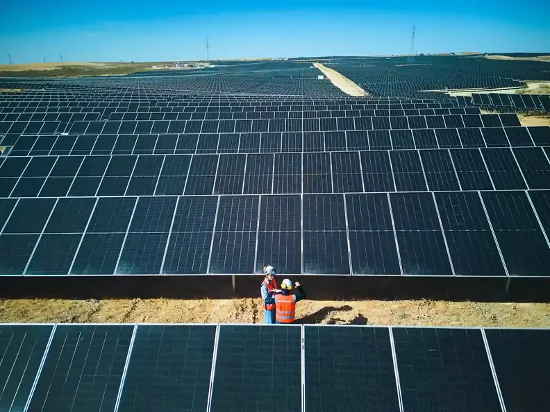 Dos trabajadores con uniforme de trabajo en medio de un parque fotovoltaico
