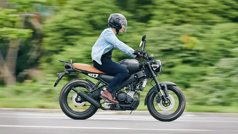 Motociclista conduciendo por carretera en una moto 150cc.