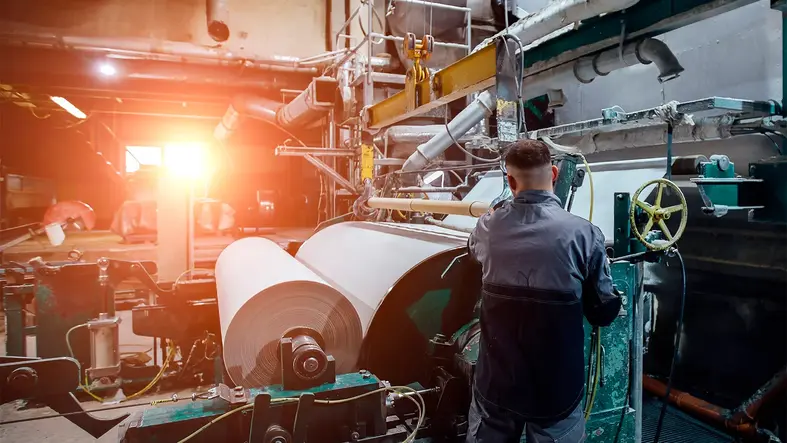 Producción de papel industrial con maquinaria pesada.