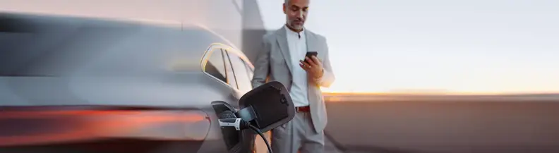 Mann mit Handy an Auto