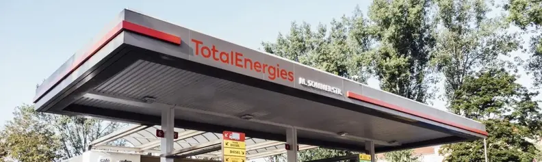 Schrägansicht auf TotalEnergies Tankstelle mit Schriftzug auf dem Dach