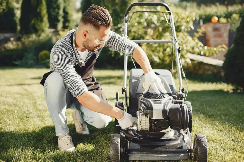 man-cutting-grass-with-lawn-mover-back-yard-male-black-apron-guy-repairs