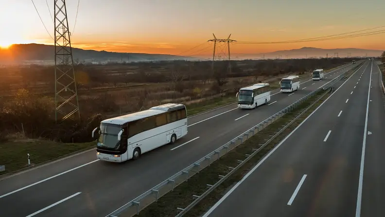 Flotilla de autobuses en carretera al amanecer.