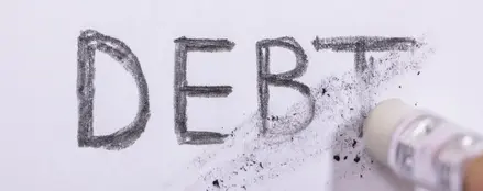 An image of the word Debt in Pencil, being erased by an eraser.