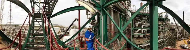 Frontalansicht auf eine Raffinerie-Mitarbeiterin, die auf eine Gasanlage blickt