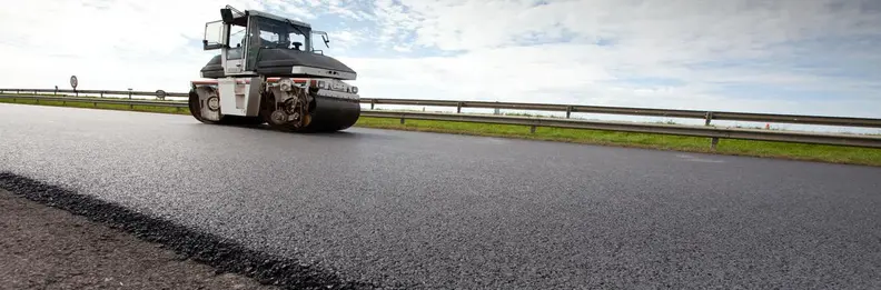 Silniční válec uhlazuje asfalt na silnici