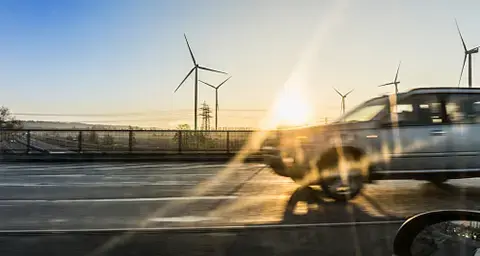 Fahrzeuge fahren an einem Windpark vorbei