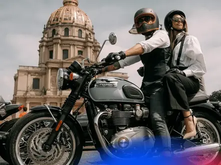 man riding a Triumph motorcycle with a female pillion