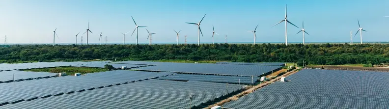 An image of a solar farm, with a windfarm in the background.