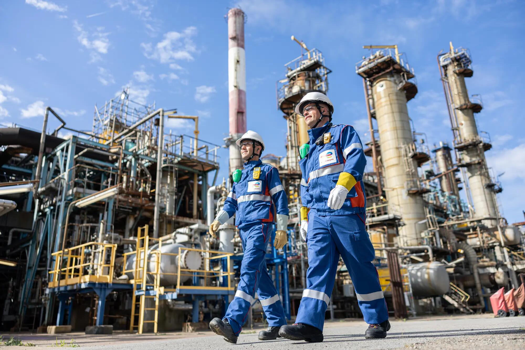 Deux opérateurs en équipement de protection individuelle marchent au coeur des unités de production