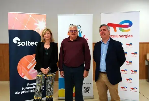 Foto de familia de tres personas delante de carteles promocionales de Soltec y TotalEnergies
