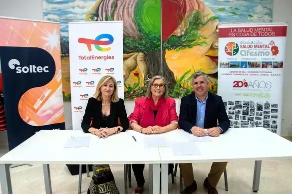 Tres personas sentadas tras una mesa con carteles corporativos detrás de las empresas a las que representan