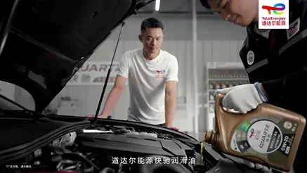 mechanic pouring TotalEnergies Quartz engine oil into a car with Lin Dan in the background