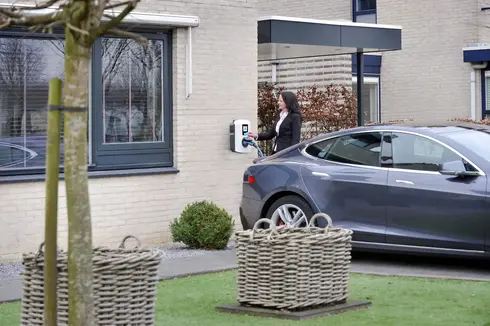 Frau lädt ihr Auto von einem Wandstecker zuhause