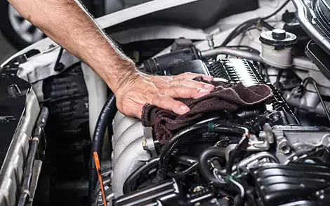 Hand mit Tuch auf einem Automotor