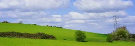 UK electricity pylon in a green field with bright blue sky